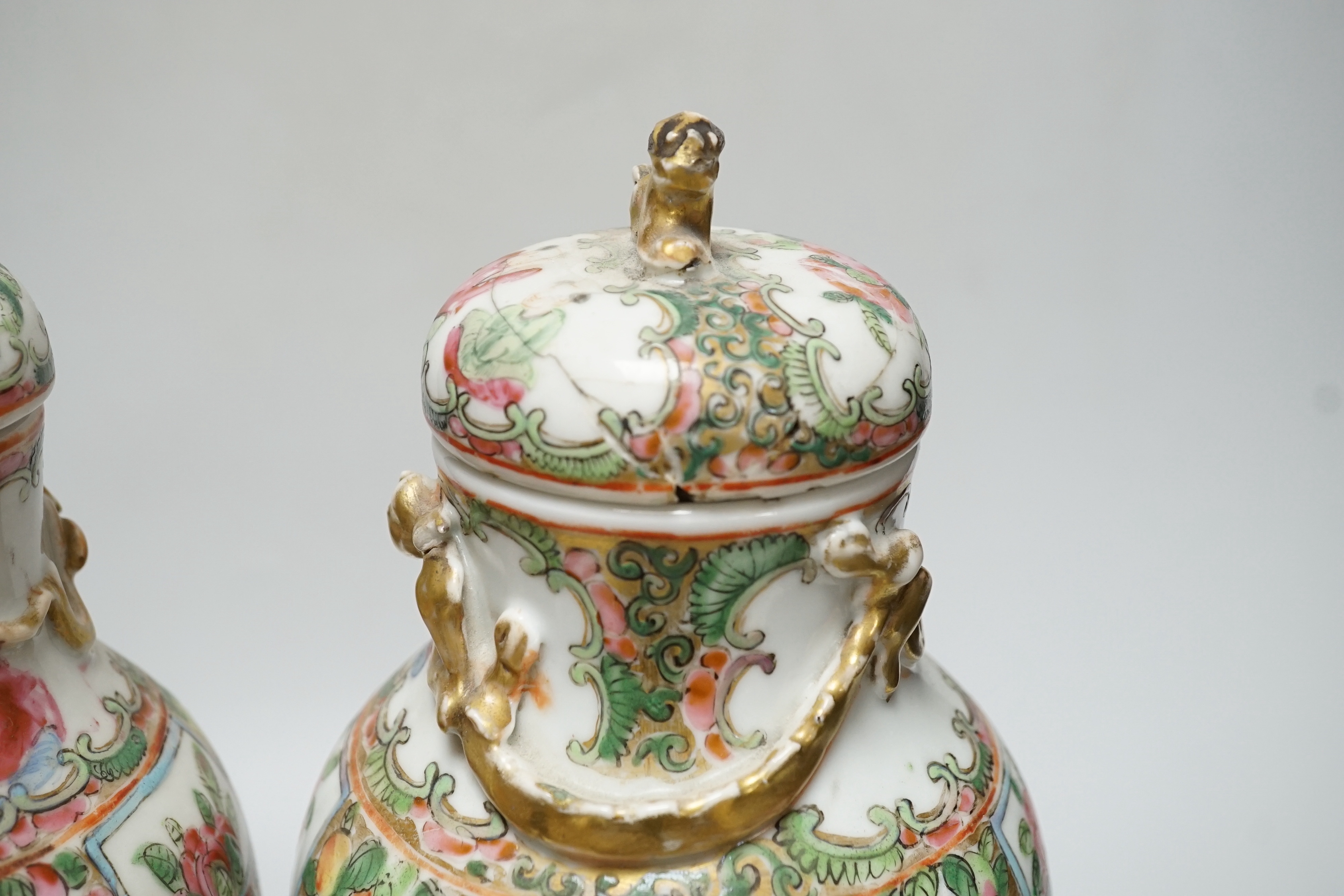 A pair of Chinese famille rose Canton baluster jars and covers with lion dog finials, 32cm high